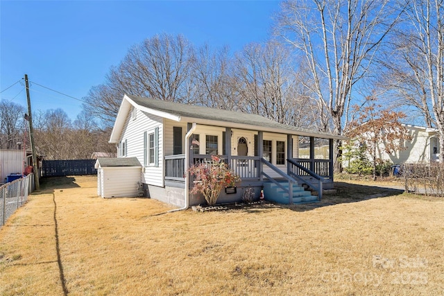 view of front of house featuring a porch, a storage shed, a front yard, a fenced backyard, and an outdoor structure