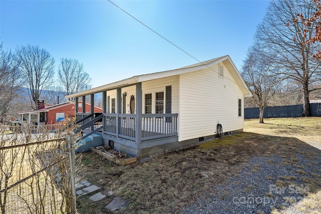 view of front of home featuring covered porch, fence, and crawl space