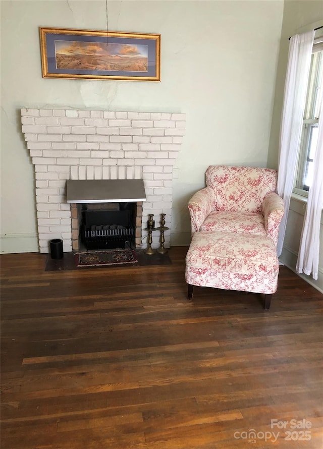 sitting room featuring a brick fireplace and wood finished floors