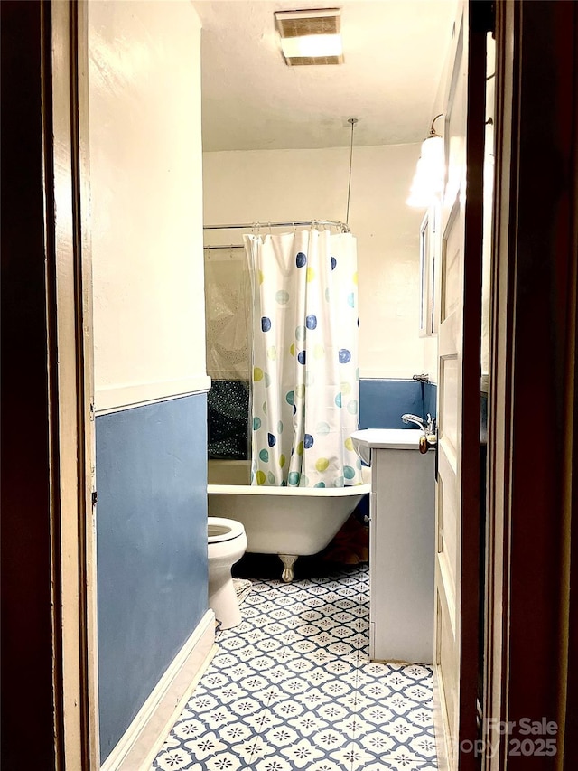 bathroom with toilet, shower / bath combo with shower curtain, vanity, and visible vents