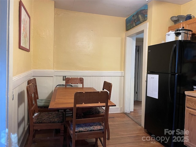 dining room with light wood-style flooring and wainscoting