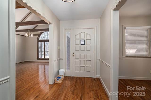 entrance foyer with a notable chandelier, wood finished floors, and beamed ceiling