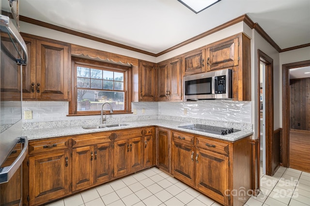 kitchen featuring black electric stovetop, stainless steel microwave, a sink, and light stone counters