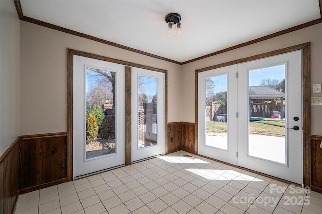 entryway featuring wood walls, ornamental molding, and wainscoting