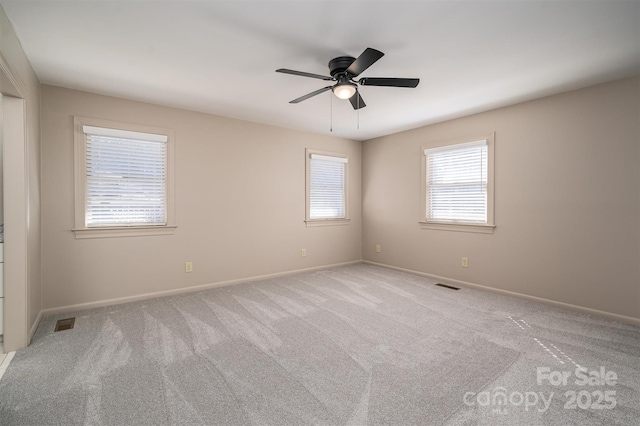 empty room with baseboards, visible vents, a ceiling fan, and light colored carpet