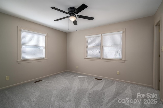 unfurnished room featuring carpet floors, a wealth of natural light, visible vents, and baseboards