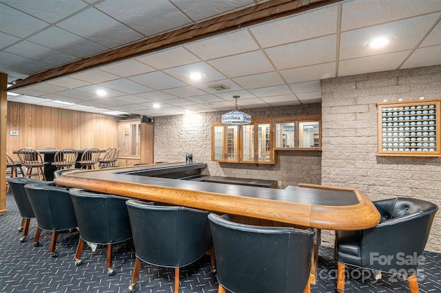 bar with dark carpet, indoor wet bar, a paneled ceiling, and pendant lighting