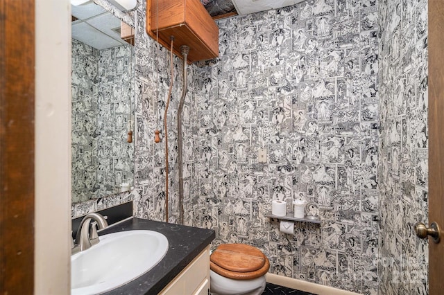 bathroom with toilet, wallpapered walls, and vanity