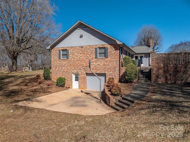 rear view of property with concrete driveway, brick siding, and an attached garage