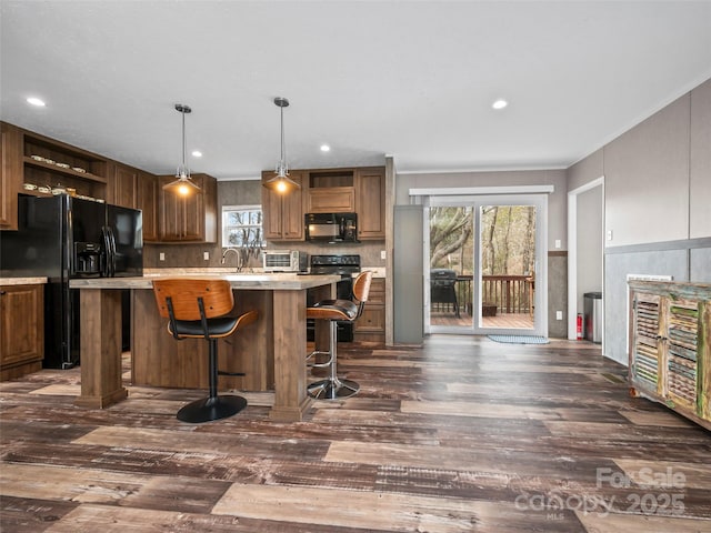 kitchen featuring dark wood finished floors, a center island, light countertops, black appliances, and open shelves