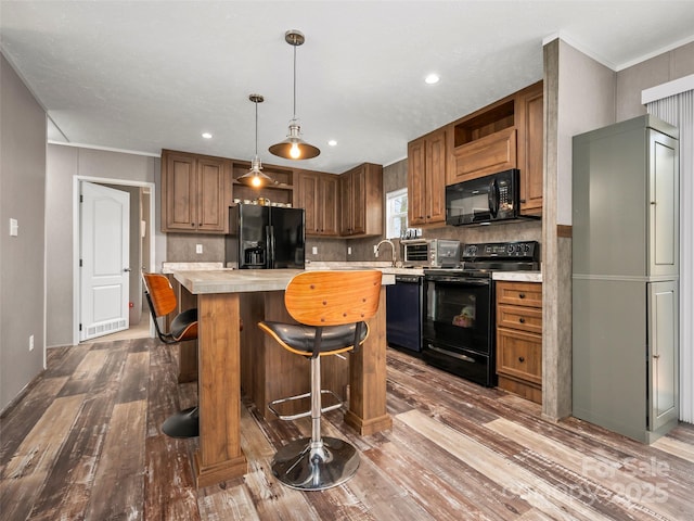 kitchen with a center island, tasteful backsplash, brown cabinetry, wood finished floors, and black appliances