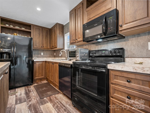 kitchen with black appliances, open shelves, a sink, and brown cabinetry