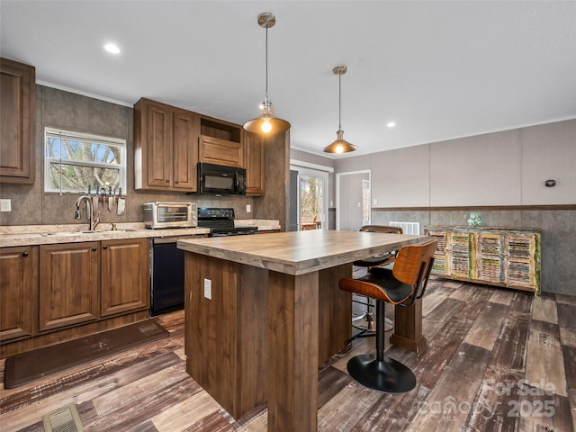 kitchen featuring butcher block countertops, dark wood-type flooring, a center island, black appliances, and decorative light fixtures