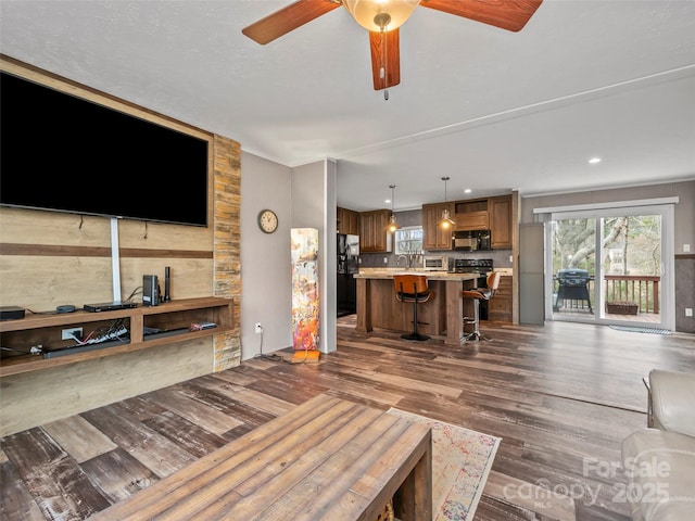 living room featuring ceiling fan, a fireplace, and dark wood finished floors