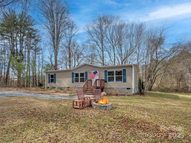 manufactured / mobile home with crawl space, a fire pit, and a front lawn