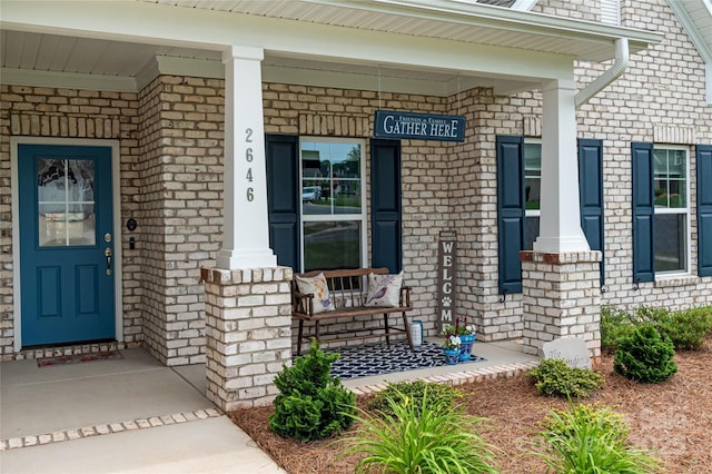 property entrance featuring covered porch and brick siding