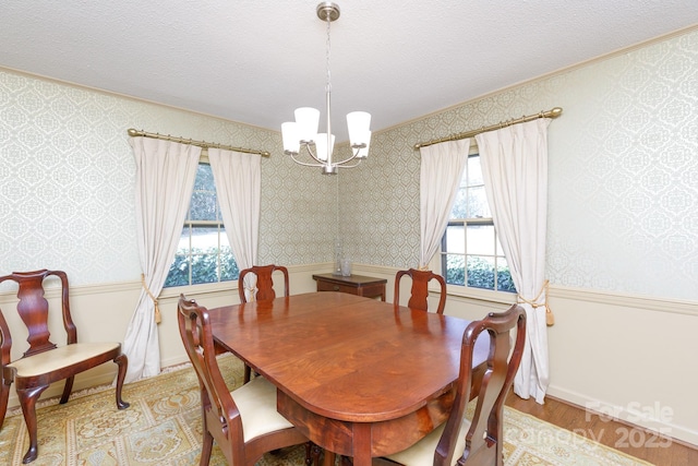 dining area featuring wallpapered walls, plenty of natural light, a textured ceiling, and an inviting chandelier