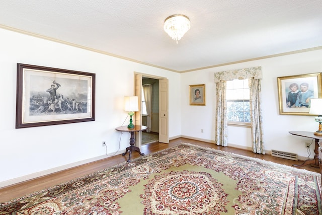 interior space featuring crown molding, visible vents, a textured ceiling, wood finished floors, and baseboards