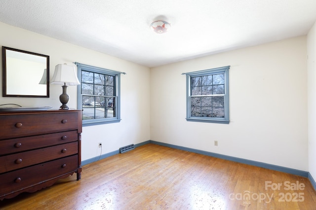 unfurnished bedroom with visible vents, light wood-style flooring, and baseboards