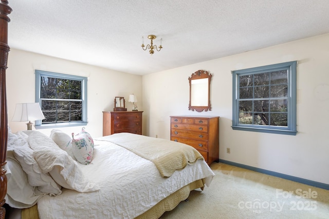 bedroom featuring light colored carpet, a textured ceiling, and baseboards