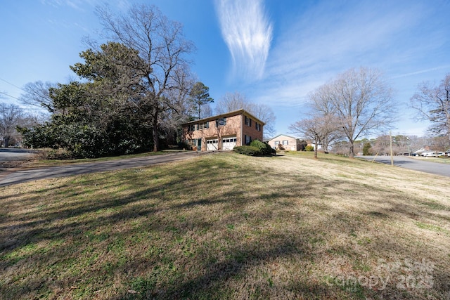 view of front of property featuring a garage, aphalt driveway, and a front lawn