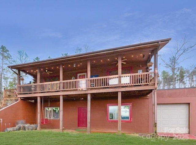 back of house featuring stucco siding, an attached garage, ceiling fan, and a yard