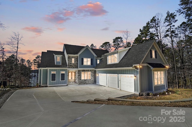 view of front of home featuring stone siding, a shingled roof, board and batten siding, and driveway