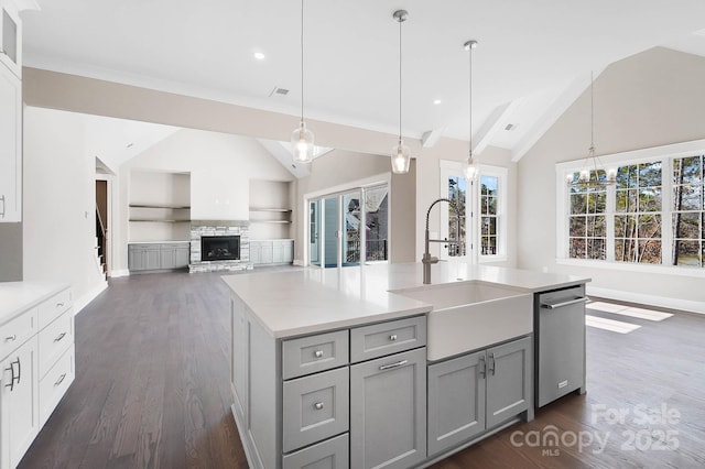 kitchen with light countertops, an island with sink, a sink, and pendant lighting