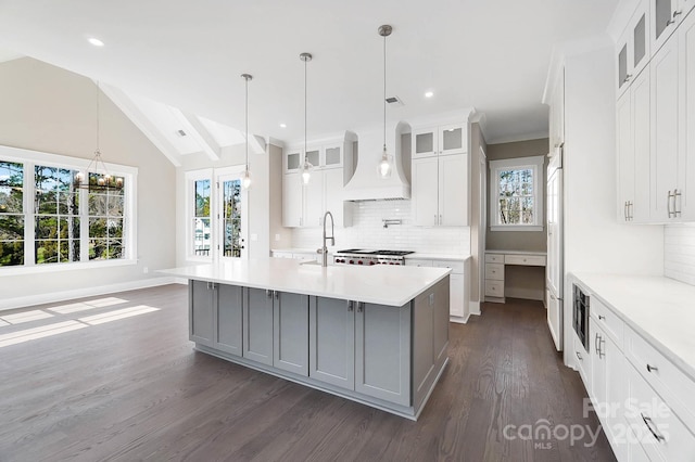 kitchen with white cabinets, light countertops, gray cabinets, an island with sink, and glass insert cabinets