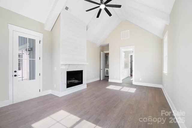 unfurnished living room with a premium fireplace, wood finished floors, visible vents, and a ceiling fan