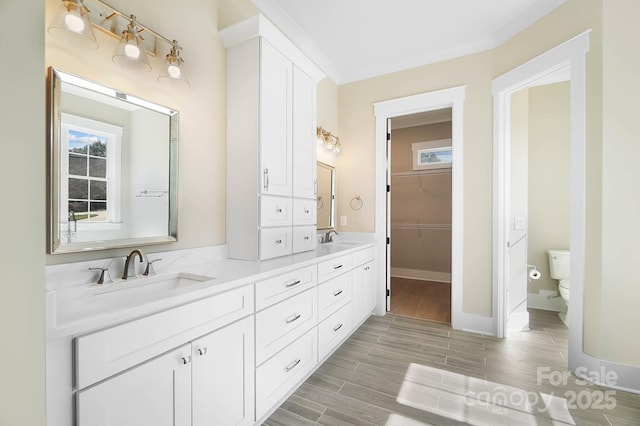 full bath featuring wood tiled floor, a sink, toilet, and double vanity