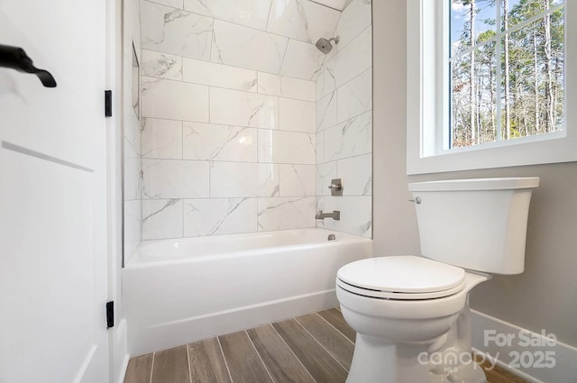 bathroom with toilet, shower / tub combination, and wood finish floors