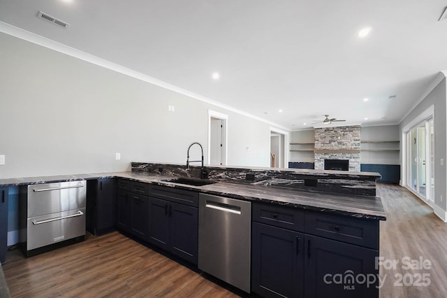 kitchen with a peninsula, a sink, visible vents, open floor plan, and dishwasher