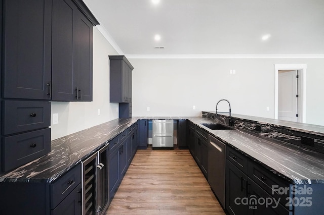 kitchen featuring ornamental molding, a peninsula, a sink, light wood-style floors, and stainless steel dishwasher