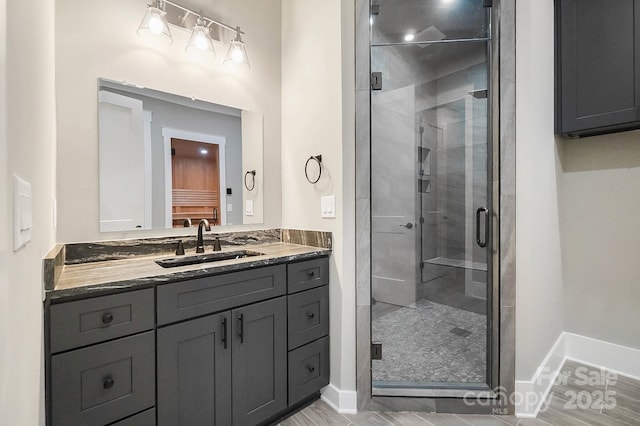 bathroom featuring a stall shower, baseboards, and vanity