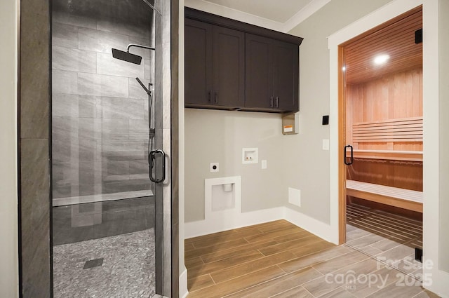 clothes washing area featuring hookup for an electric dryer, wood finish floors, washer hookup, a sauna, and cabinet space