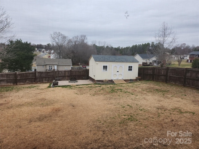 view of yard featuring an outdoor fire pit, a shed, a fenced backyard, and an outdoor structure