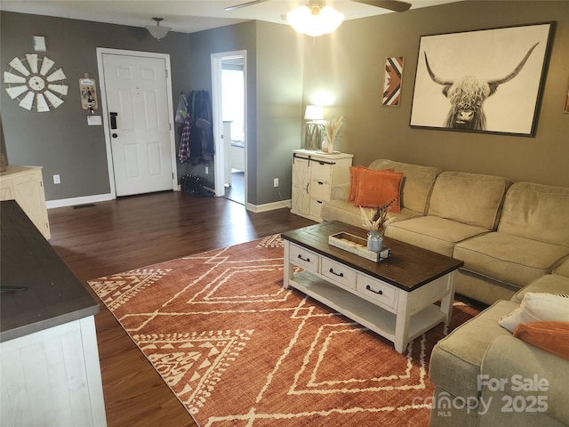 living room with ceiling fan, visible vents, baseboards, and dark wood-type flooring