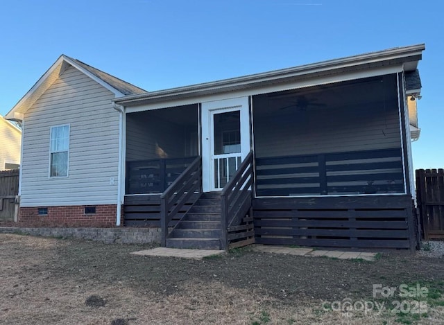 view of front facade with crawl space, a sunroom, and fence