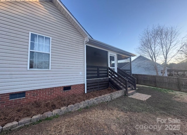 view of side of home featuring crawl space, a sunroom, fence, and a ceiling fan