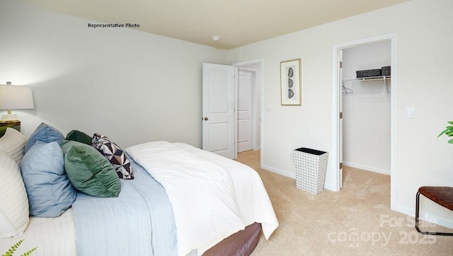 bedroom with a walk in closet, baseboards, a closet, and light colored carpet