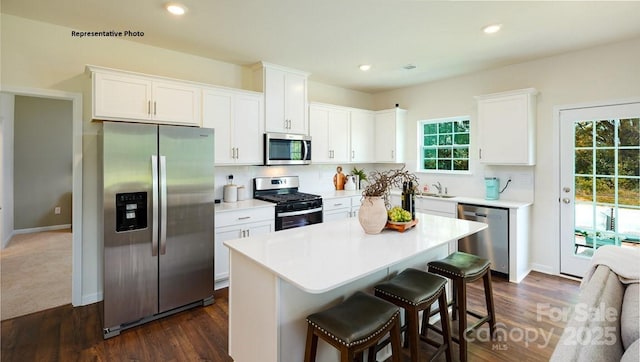 kitchen featuring white cabinets, stainless steel appliances, and a breakfast bar area