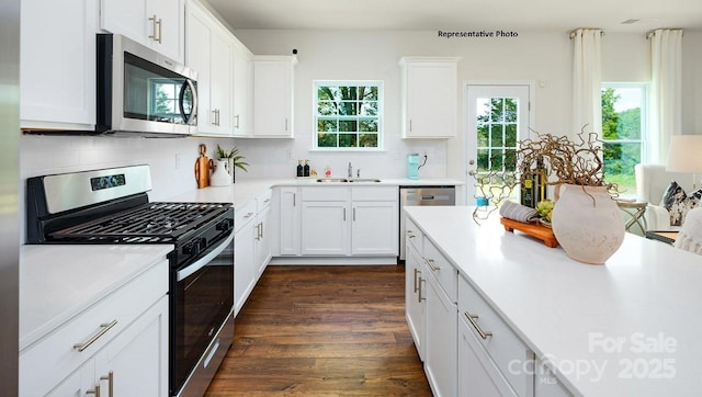 kitchen featuring a sink, decorative backsplash, stainless steel appliances, light countertops, and white cabinetry
