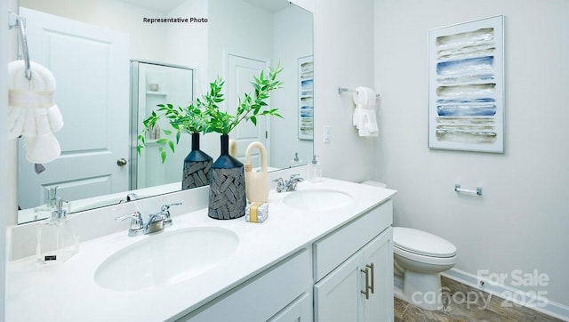 bathroom featuring double vanity, toilet, a stall shower, and a sink