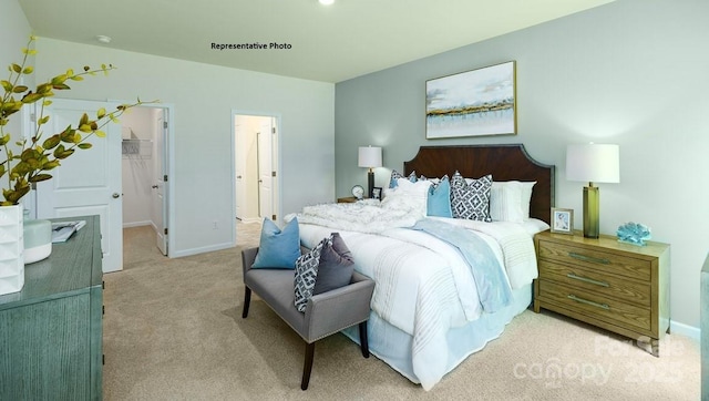 bedroom with baseboards, a spacious closet, and light colored carpet