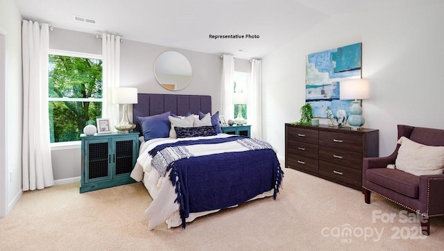 bedroom featuring light colored carpet, vaulted ceiling, and visible vents