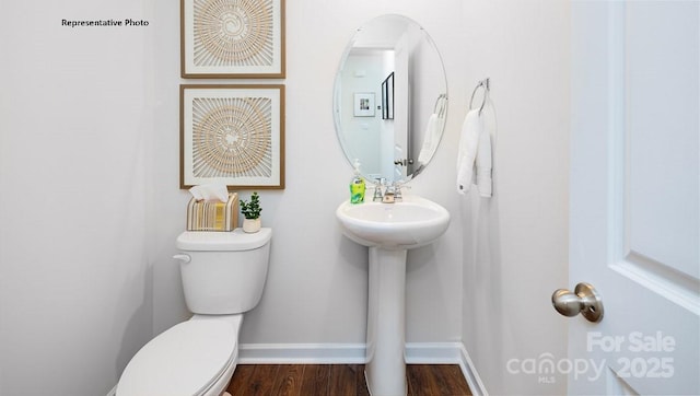 bathroom with a sink, toilet, wood finished floors, and baseboards