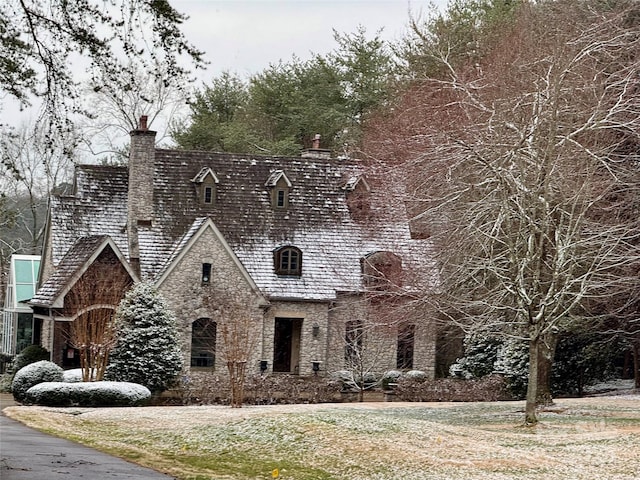 view of front of property with a high end roof, stone siding, and a chimney