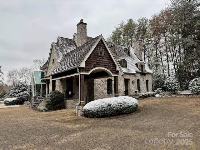 view of front of home with stone siding and a chimney