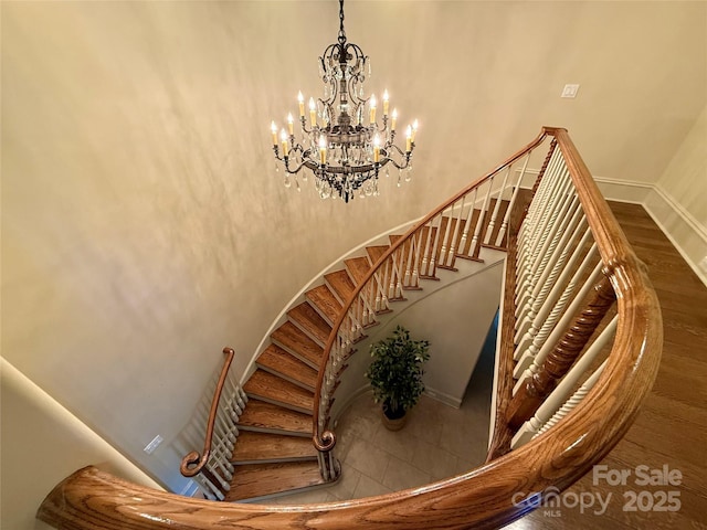 stairs with a high ceiling, baseboards, and a chandelier